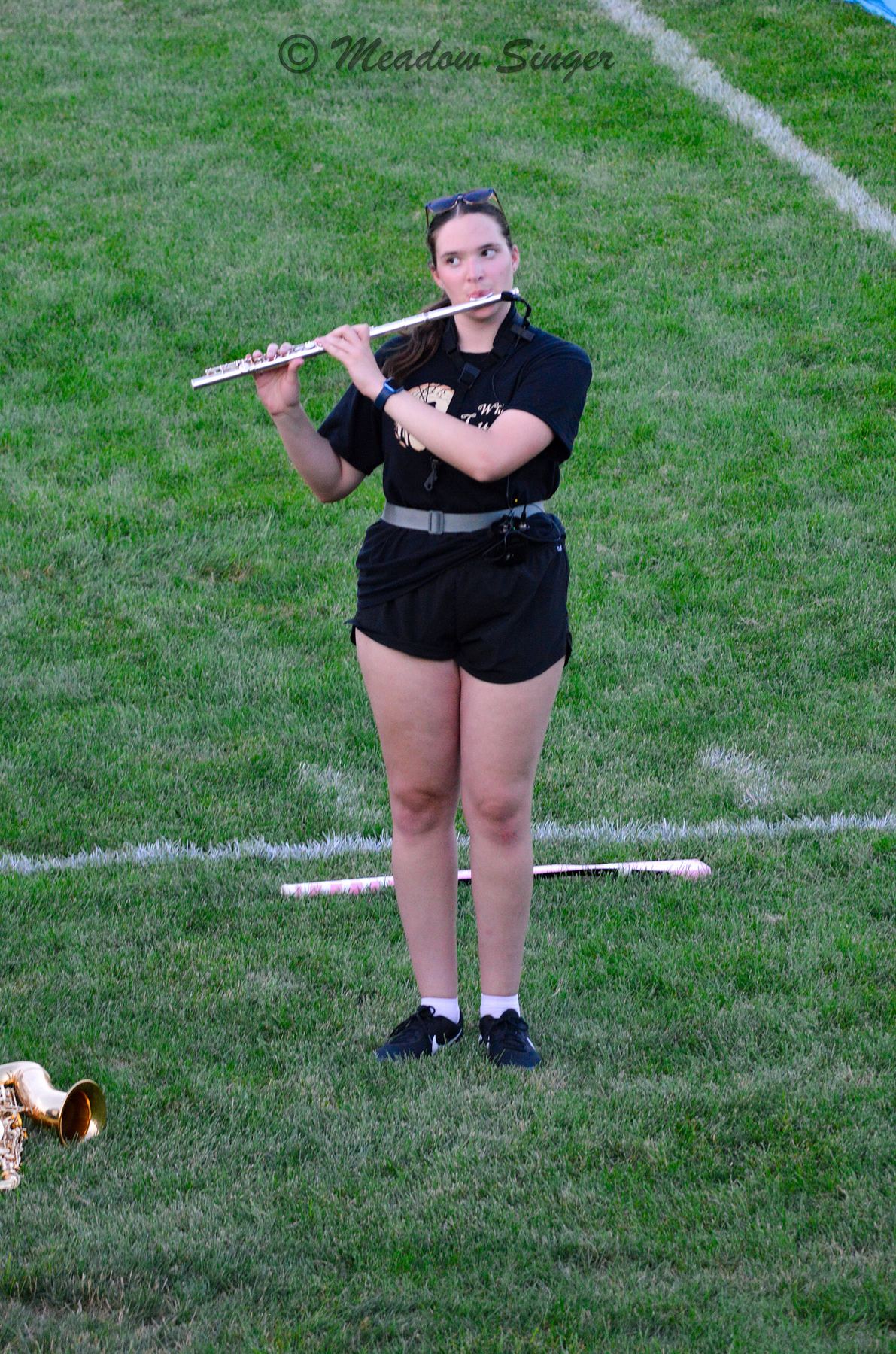 A marching band member playing the flute on a football field
