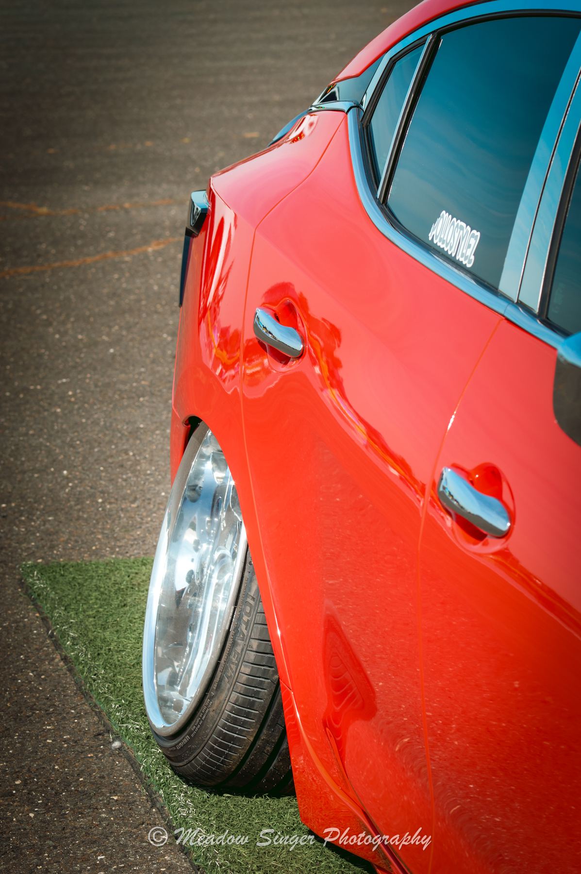 The side of a bright red coupe with polished wheels