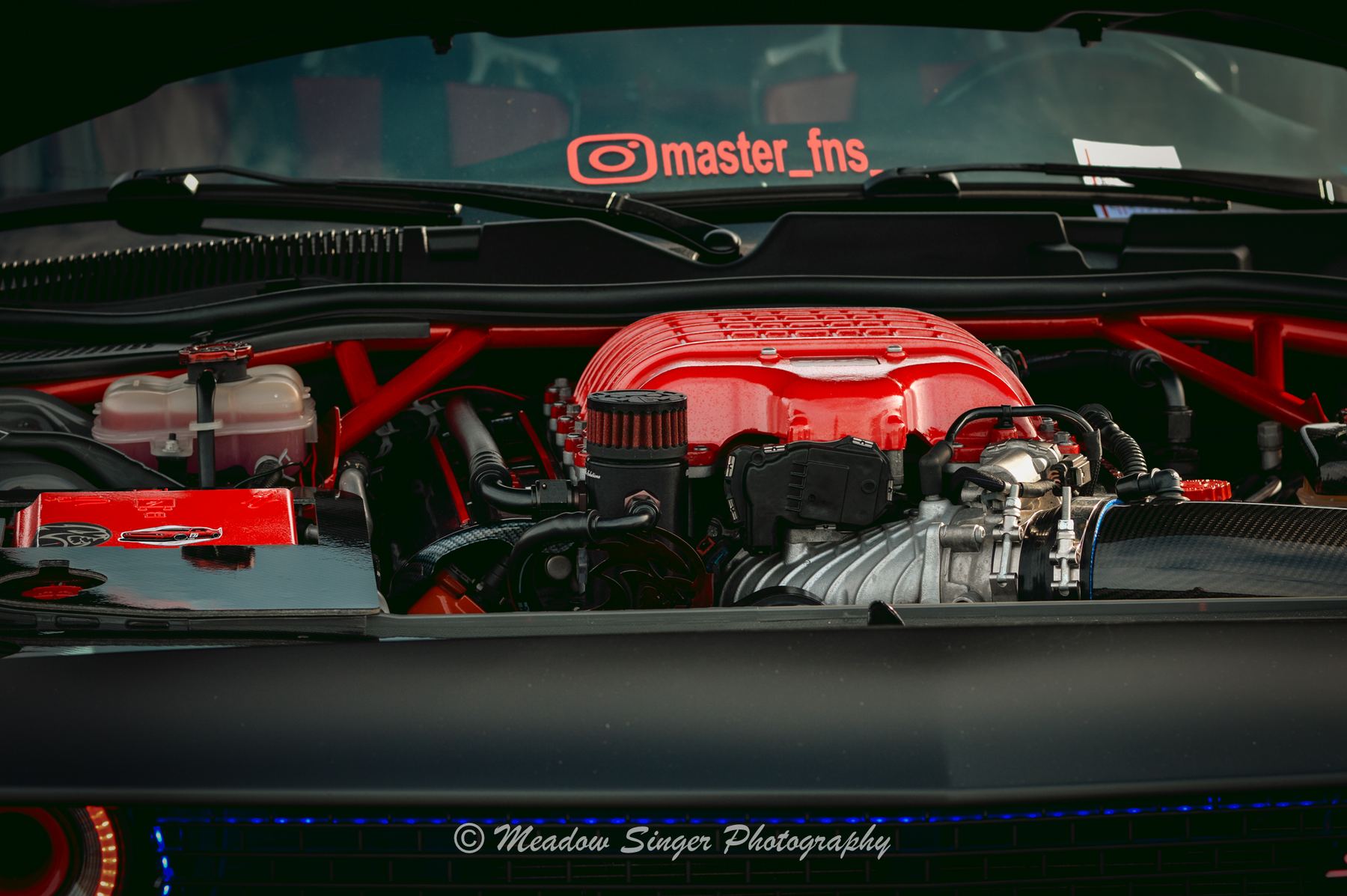 A red engine cover under an open hood