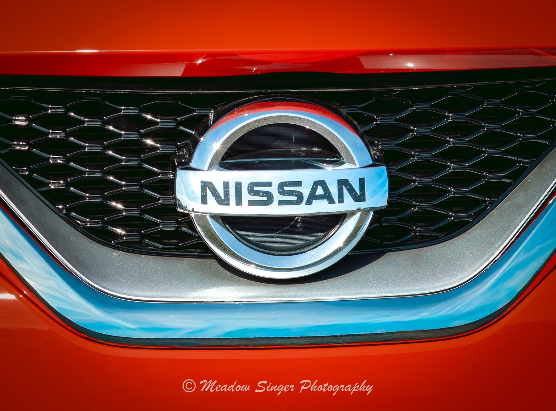 A chrome Nissan badge on a red grille