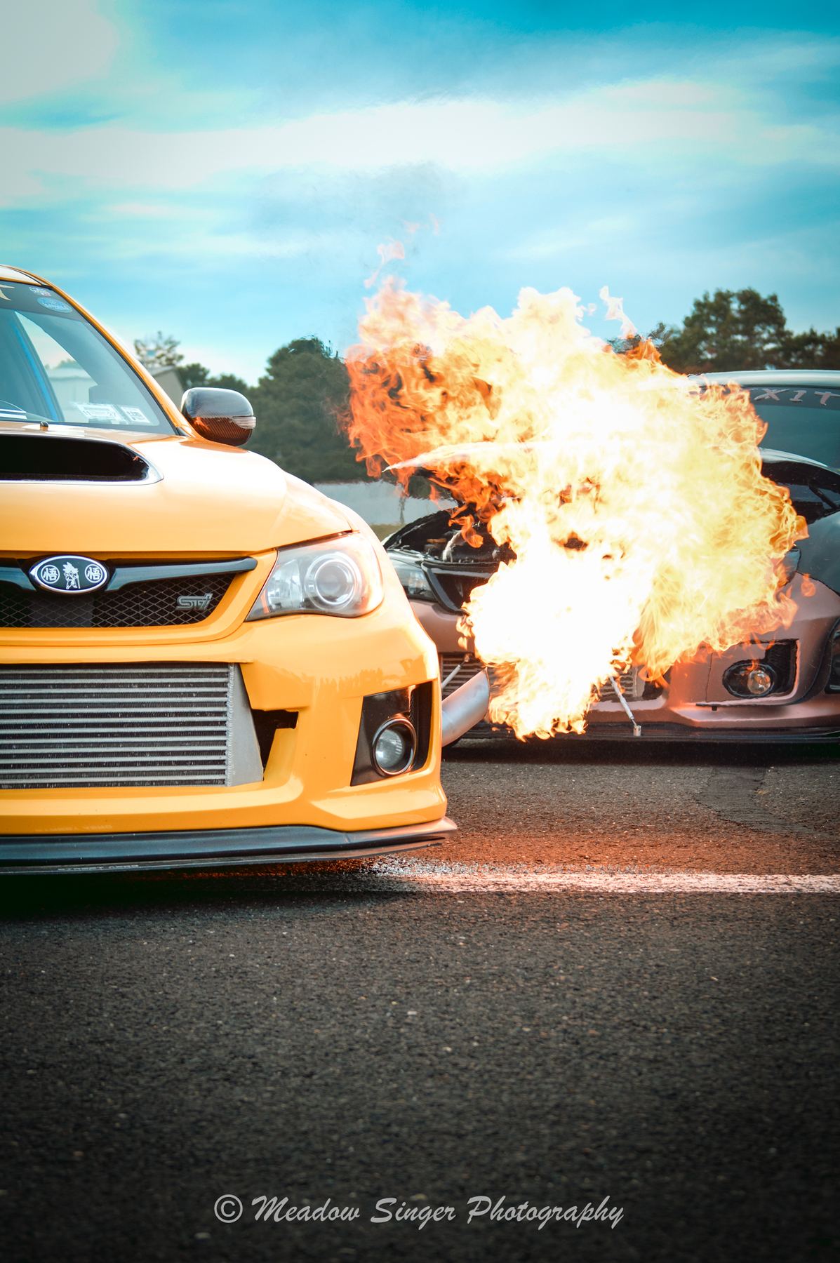 A yellow rally car with a fireball behind it