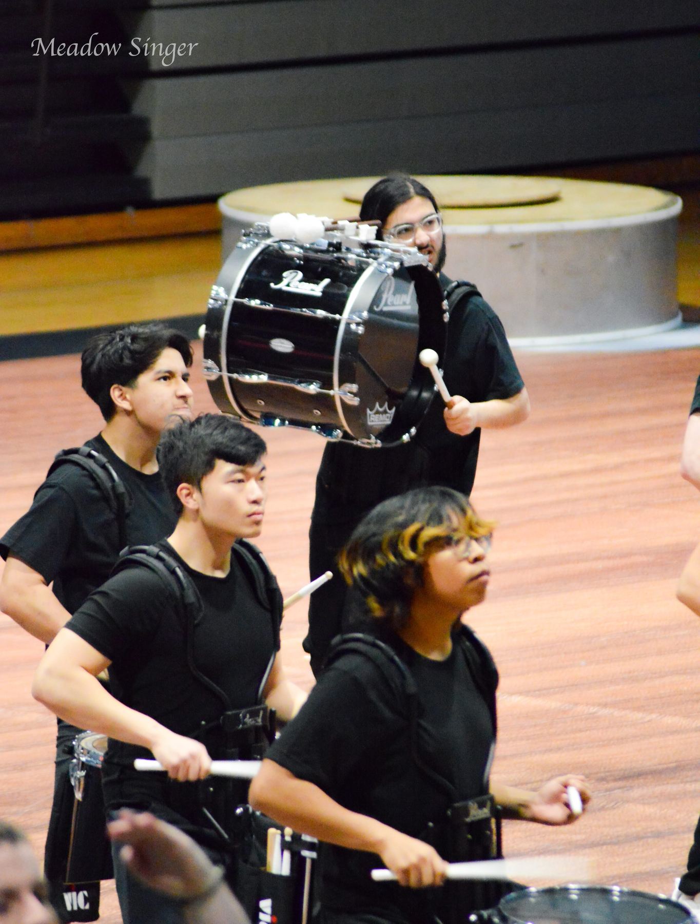 A drumline playing snare drums in a gym