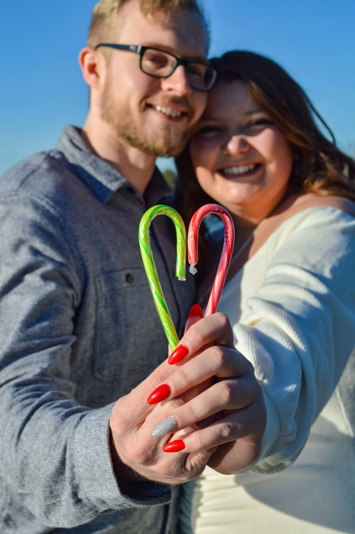 A couple holding two candy canes together in the shape of a heart