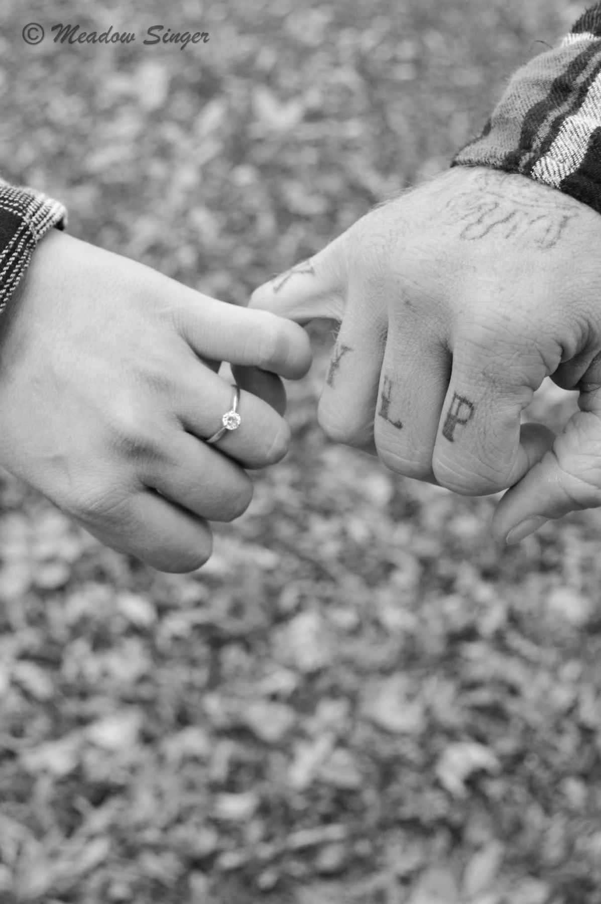 Black and white close up of two hands with an engagement ring