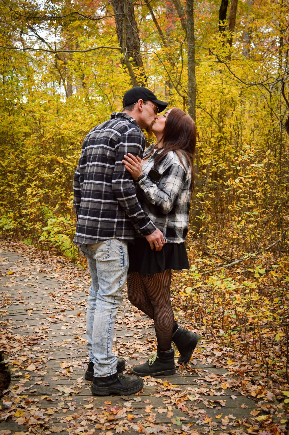 A couple kissing on a leafy path in autumn woods