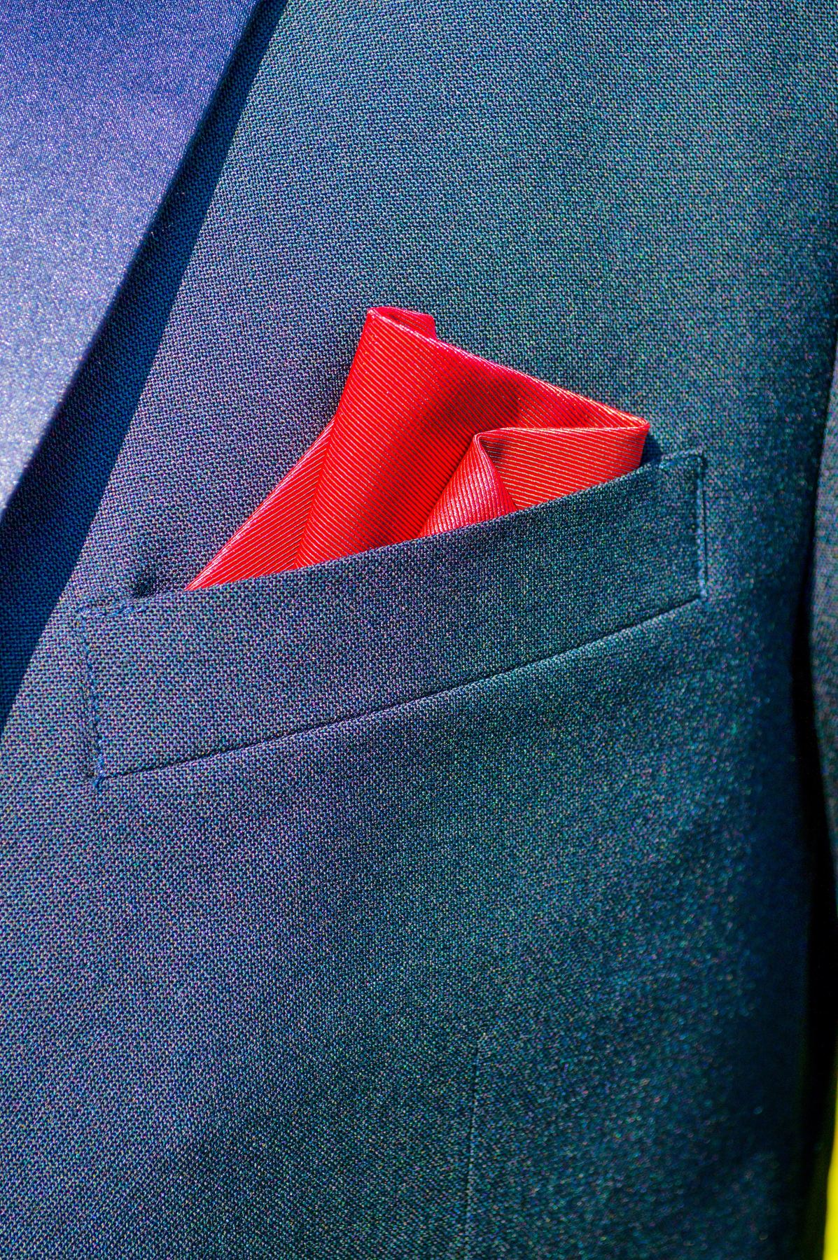 A red pocket square in a navy suit jacket
